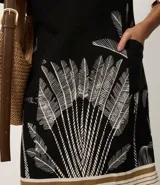 Vestido corto negro de viscosa y lino, con escote en V, mangas cortas y estampa gráfica de follaje blanco en la parte inferior, complementada con franjas horizontales en el ruedo.