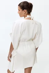 Vestido corto estilo túnica color blanco, de diseño oversized y mangas cortas, con escote en V pronunciado y cordón ajustable en la cintura.