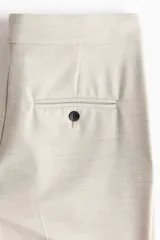 Pantalón tobillero de corte bootcut, color beige, con cintura estándar, raya marcada al frente y en la espalda, y cierre con pretina prolongada y botón.