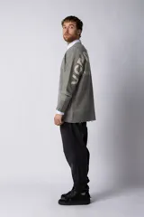 Sweater oversize de tejido de punto en color gris, con cuello redondo, puños y ruedo acanalados con detalles de desgaste. Presenta un diseño minimalista con logo tejido en la espalda.