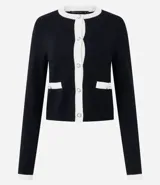 Cardigan de punto color blanco con detalles en negro en cuello, puños y tapeta frontal. Presenta cierre frontal con botones perlados y dos bolsillos delanteros falsos con solapa bicolor.