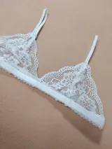 Bralette de encaje blanco con diseño triangular, tirantes finos regulables y banda elástica inferior.