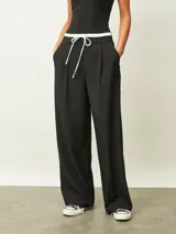 Pantalón de vestir negro de corte recto y tiro alto, con cintura elástica blanca y cordón ajustable. Presenta pinzas frontales y bolsillos laterales.