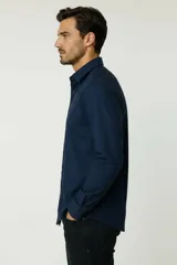 Camisa blanca de algodón, de diseño holgado y manga larga, con cuello camisero y cierre frontal de botones.