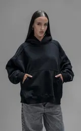 Hoodie oversize de corte crop, color negro, confeccionado en frisa gamuzada de algodón. Presenta capucha forrada, mangas largas con puños elásticos y bolsillo tipo canguro frontal.