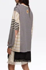 Remera manga larga oversize de corte relajado, confeccionada en 100% algodón orgánico con cuello redondo. Presenta un diseño de rayas horizontales en combinación de tonos azul marino, beige, blanco y detalles en rojo.