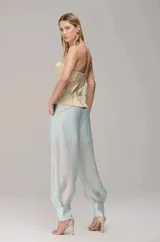 Pantalón de organza translúcida en color celeste, de corte amplio con efecto abullonado, pliegues frontales y puños ajustados en los tobillos con cierre lateral.