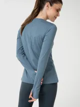 Polera deportiva de manga larga con cuello redondo, confeccionada en tejido técnico de efecto jaspeado. Presenta aberturas para los pulgares en los puños y un pequeño logo bordado en el pecho.