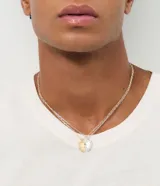 Collar doble de cadena fina con acabado bicolor, compuesto por dos eslabones de diferente tono metálico. Presenta un dije central en forma de corazón dividido en dos piezas, una dorada y otra plateada.