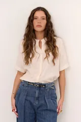 Camisa de manga corta color blanco con cuello mao y cierre frontal de botones. Presenta detalles bordados tono sobre tono en el canesú y diseño de corte recto.