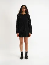Vestido corto negro con textura de rayas verticales claras, escote redondo y mangas largas.