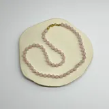 Collar de cuentas de cuarzo rosa de 6mm de diámetro, con separadores de hilo rosado y cierre de mosquetón de acero hipoalergénico con baño dorado.