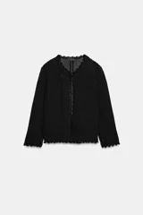 Chaqueta de punto calado con diseño pointelle, cuello redondo y manga larga. Presenta cierre frontal con corchete oculto y terminaciones con detalle de ondas en puños y ruedo.