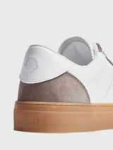 Championes Moncler modelo Monaco, de color blanco con detalles en gamuza gris en los ojales y talón, y suela de goma marrón translúcida.