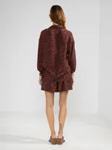 Camisa de manga larga color rosa con rayas verticales rojas y estampado de flores rojas. Con cuello camisero, puños elastizados y lazos regulables en los costados del ruedo.