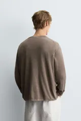 Jersey de manga larga, cuello redondo y calce relajado, color negro con efecto lavado y textura tejida.