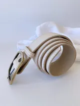 Cinto de cuero color crudo con hebilla rectangular de metal color bronce envejecido.