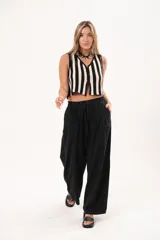 Pantalón negro de pierna súper amplia, confeccionado en denim fino y liviano con caída fluida. Tiene cintura elastizada con lazo regulable, bolsillos laterales y pinzas en la delantera.