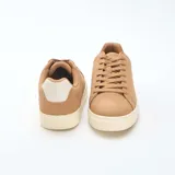 Zapatillas bajas de estilo urbano en color marrón, con suela y detalle en el talón en color crema. Presentan cierre mediante cordones al tono y diseño minimalista.