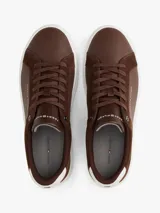 Zapatillas de corte bajo Tommy Hilfiger confeccionadas en una combinación de piel nobuk y piel lisa en color marrón. Presentan suela de goma blanca, detalle de ventilación lateral, logo de la marca en la lengüeta, lateral y talón, y cierre mediante cordones.