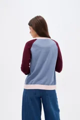 Cardigan de punto con diseño color block, presenta cuerpo en color celeste, mangas en color bordó y detalles de botones y bordes en color rosado. Posee cuello redondo y mangas largas.