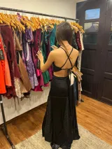 Vestido largo sin mangas con escote en V halter y aberturas laterales (cut-outs) en la cintura. El cuerpo superior presenta un llamativo diseño estampado multicolor, mientras que la falda larga es de tejido texturizado brillante en color verde esmeralda con inserciones godet en el ruedo.