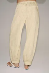 Pantalón bombacho de tiro medio, confeccionado en hilatura con mezcla de viscosa, con estampado de rayas verticales en tonos beige y amarillo claro, cintura elástica ajustable con cordón y puños en los tobillos.