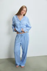 Pijama de dos piezas confeccionado en viscosa, compuesto por una camisa de manga larga con cuello solapa y cierre frontal de botones, y un pantalón de corte recto y holgado. Presenta un diseño de rayas verticales en tonos azul y blanco.