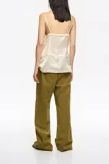 Pantalón de corte recto y tiro bajo, color crudo, con bolsillos frontales tipo alforja y cintura ajustable con cordón.