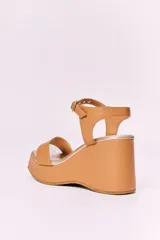 Sandalias de cuero negras con plataforma y tacón de 10 cm. Tienen una tira ancha en la parte delantera y una tira ajustable con hebilla alrededor del tobillo, ambas con detalles de tachas plateadas.