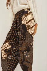 Pantalon de corte holgado tipo bombacho con estampado batik tradicional en tonos azul marino, beige y dorado. Presenta cintura elástica y diseño fluido.