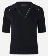 Blusa negra de punto con cuello polo, escote en V y mangas cortas. Detalle de mini perlas aplicadas en el cuello.