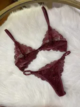 Conjunto de lencería de encaje color bordó, compuesto por un corpiño triangular con cierre frontal y una tanga regulable con tiras laterales.