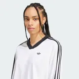 Blusa cropped de manga larga Adidas Adicolor en color blanco, con cuello en V y puños acanalados en negro. Presenta las tres tiras clásicas de la marca en color negro a lo largo de las mangas y el logo del trifolio bordado en el pecho.