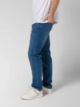 Pantalón de jean azul índigo con diseño clásico de cinco bolsillos, cierre de cremallera y botón metálico. Presenta corte de pierna delgada, remaches con logo en bolsillos delanteros y parche de marca en la cintura trasera.