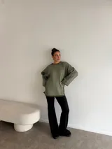 Pantalón tipo oxford de tiro alto, color negro, con corte ajustado en la parte superior y acampanado desde la rodilla hacia abajo.
