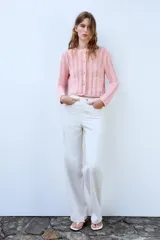 Chaqueta de punto pointelle en color rosado, con cuello redondo, manga larga y bolsillos delanteros de parche. Cuenta con cierre frontal de botones claros.