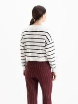 Sweater de tejido liviano color blanco con rayas horizontales negras, escote redondo, mangas largas y hombros caídos. Cuenta con pequeños bordados decorativos en el frente que representan una abeja, una flor y una frutilla.