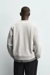 Sudadera de cuello redondo y manga larga, confeccionada en tejido de algodón pesado con interior de rizo ligeramente afelpado. Presenta un corte relajado y acabados en rib en puños y ruedo.