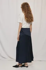 Falda larga de color negro, calce al cuerpo y caída fluida, confeccionada en tejido satinado con detalle de recorte diagonal en la parte delantera y cintura elástica.