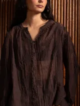 Blusa de tela liviana color bordó, con escote en V y detalles de bordado floral tono sobre tono. Presenta mangas largas con leve volumen y puños abotonados.