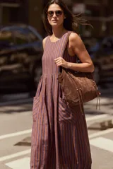 Vestido maxi sin mangas de corte fluido, con diseño a rayas verticales en tonos azul y marrón. Presenta cuello redondo y bolsillos frontales aplicados.