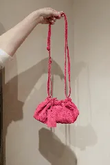 Cartera tipo sobre de cuero color fucsia, con diseño fruncido y cierre de cordón. Incluye una correa ajustable y extraíble para usarla como cartera o como sobre de fiesta.
