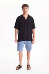 Camisa de viscosa negra de manga corta, con cuello camisero y cierre frontal de botones, de corte oversize.