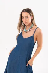 Vestido largo de denim fino y liviano, color azul, con breteles finos, escote en V y falda amplia con recortes verticales y bolsillos laterales.