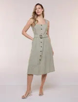 Vestido midi abotonado verde melange, con escote recto, tirantes anchos y falda de calce recto con vuelo sutil. Tiene abotonadura frontal completa con botones estilo carey, cinto textil con hebilla para ajustar la cintura y bolsillos laterales.