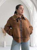 Campera marrón de corderito con cuello solapa, cierre frontal con cremallera, bolsillos laterales y detalles en cuero sintético marrón.