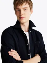 Camisa de sarga de puro algodón teñido en prenda, color azul marino, con cuello abotonado, bolsillo de parche en el pecho, puños redondeados con botón, cinta distintiva en el interior del cuello y logo de Tommy Hilfiger bordado en el bolsillo del pecho.