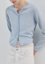 Cardigan de punto fino color celeste, con cuello redondo, manga larga y cierre delantero con botones.