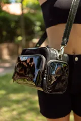 Bolso bandolera negro de cuero, con correa ajustable y desmontable. Tiene un compartimento principal con cierre y dos bolsillos frontales con cierre.